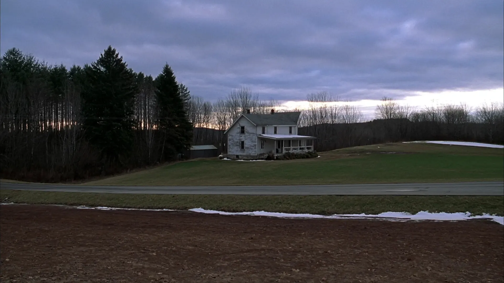 Western Reserve farmhouse and open lawn on a rolling rural lot in Northeast Ohio at winter dusk